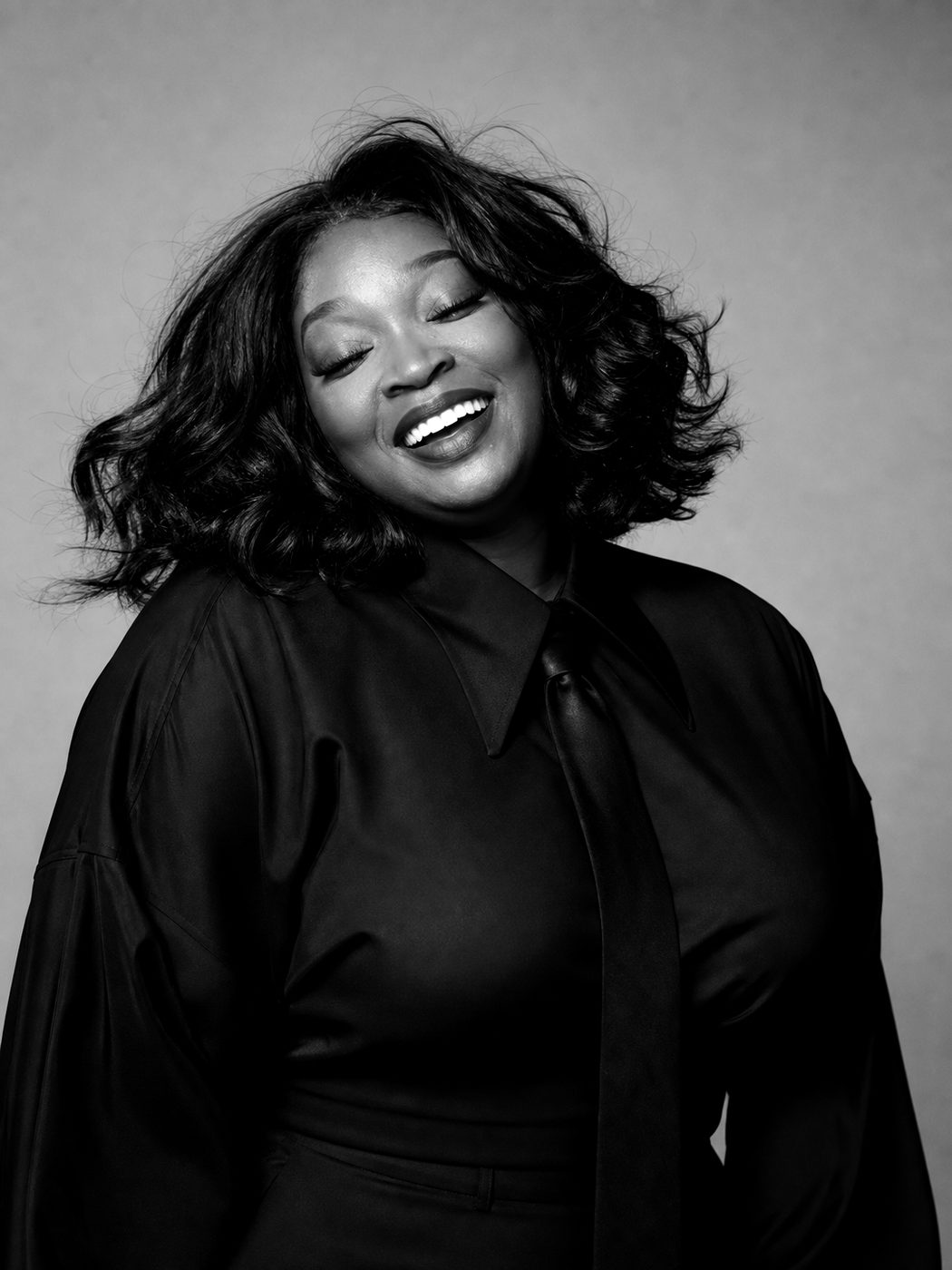 Black and white portrait of Lou Taylor smiling with her eyes closed